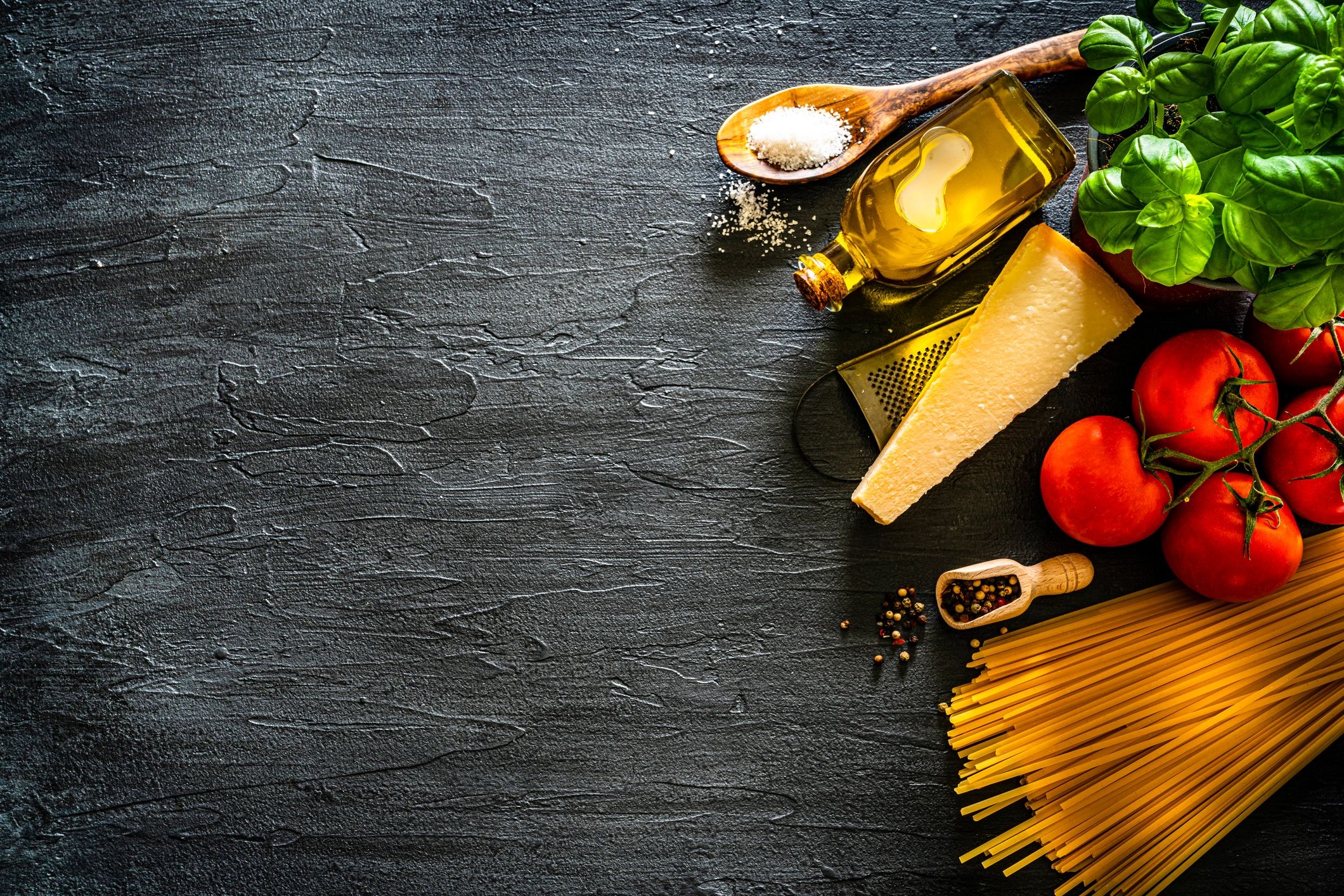 Uncooked pasta and ingredients forming a frame on a dark background